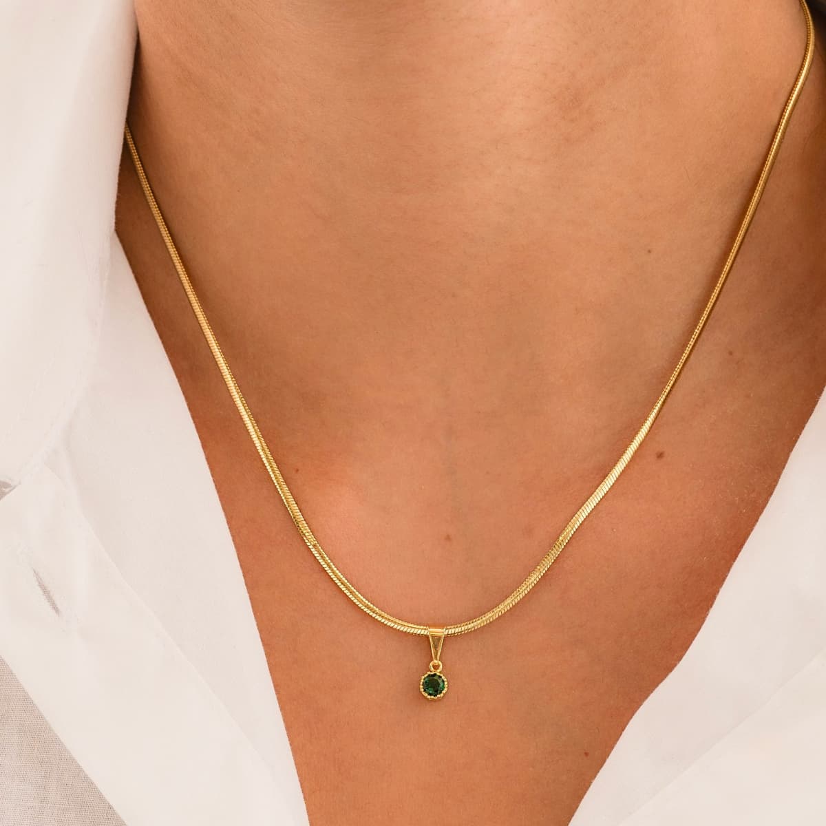 Cadena serpiente con dije de piedra blanca en cuello de mujer